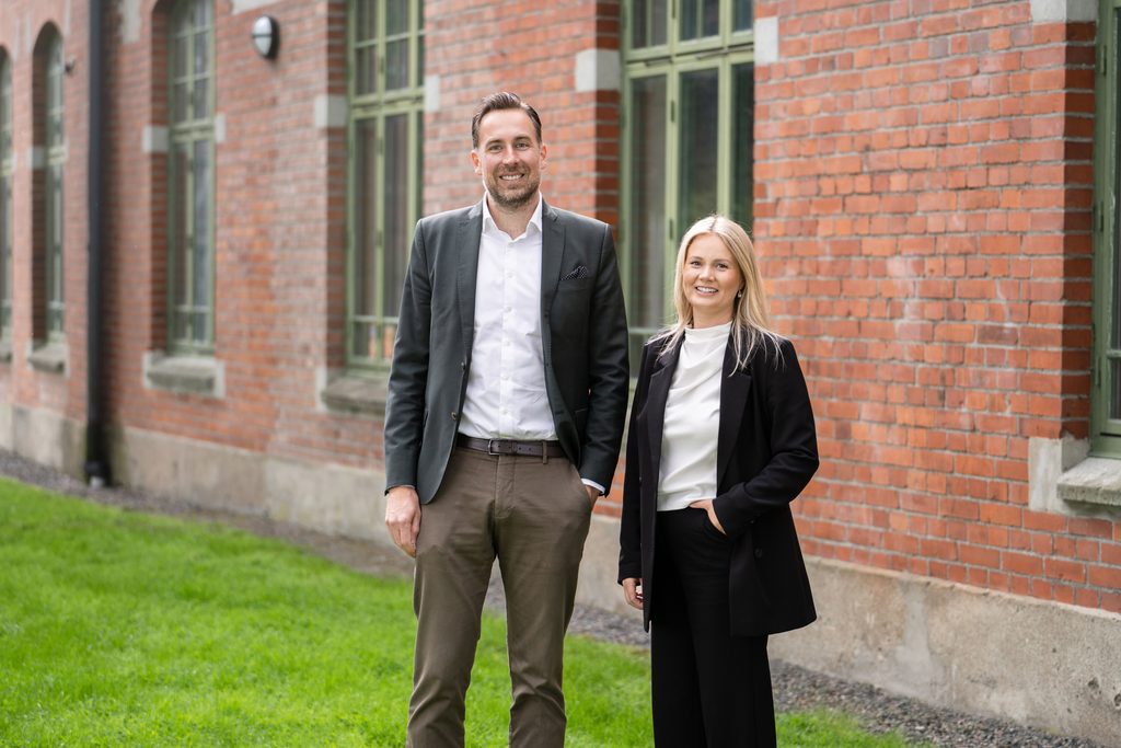 Mathias Martinsson och Malin Ryling, fastighetsmäklare och partners på Residence Christie’s, framför en tegelbyggnad.