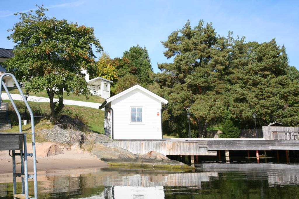 Lågupplöst Sandstrand och vinterbonad sjöstuga, gästhus
